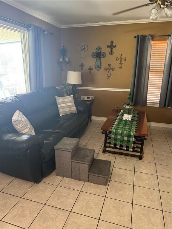 living area with ceiling fan, baseboards, light tile patterned flooring, and ornamental molding