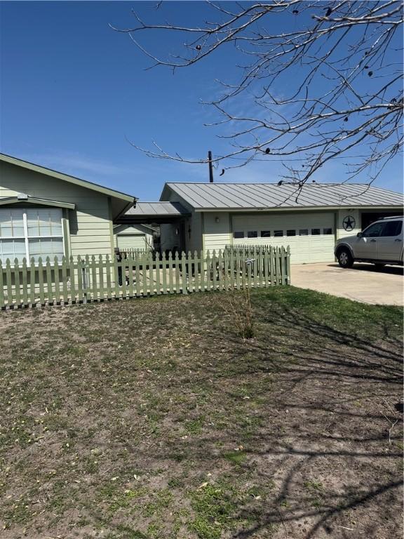 view of yard with driveway, a garage, and a fenced front yard