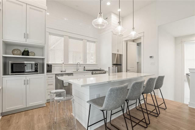 kitchen featuring a breakfast bar area, light wood-style flooring, stainless steel appliances, a sink, and a center island