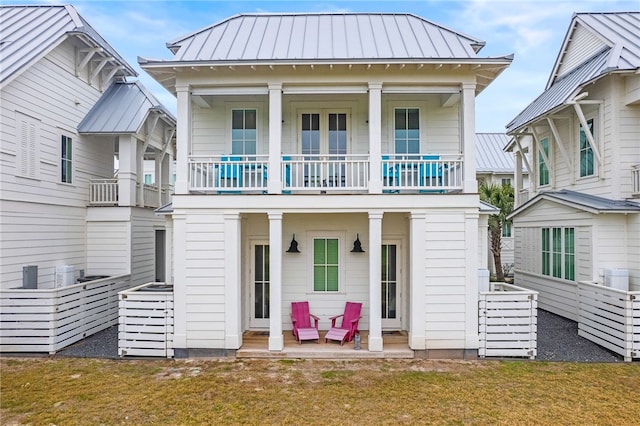 view of front facade featuring a patio area, metal roof, a standing seam roof, and a front yard