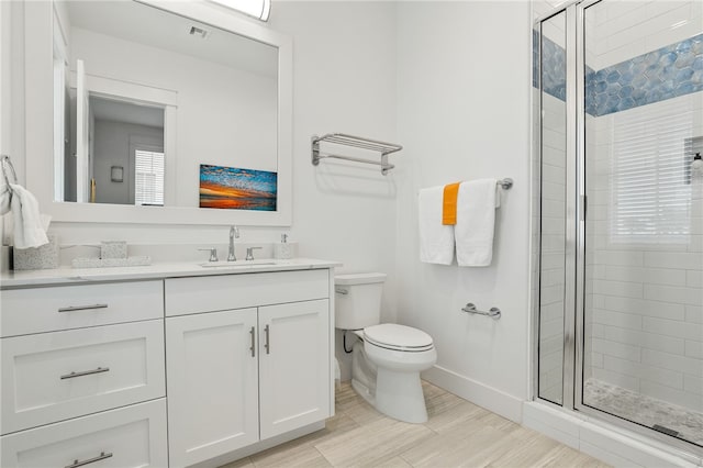 bathroom with vanity, a shower stall, toilet, and baseboards