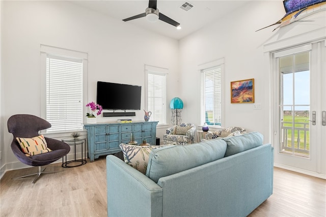 living area featuring light wood-style floors, plenty of natural light, visible vents, and ceiling fan