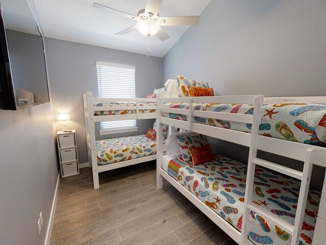 bedroom featuring wood-type flooring, vaulted ceiling, and ceiling fan