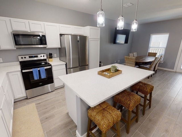 kitchen with light hardwood / wood-style flooring, white cabinetry, a kitchen breakfast bar, and stainless steel appliances