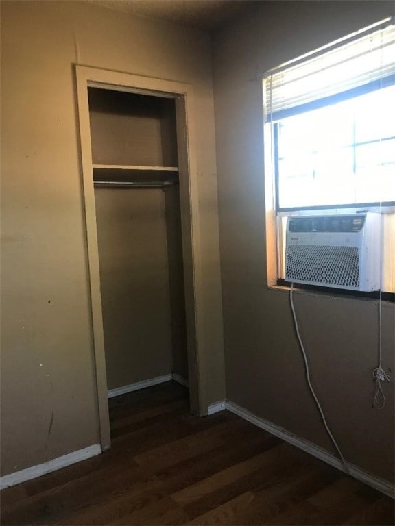 unfurnished bedroom with dark hardwood / wood-style flooring, a closet, and cooling unit