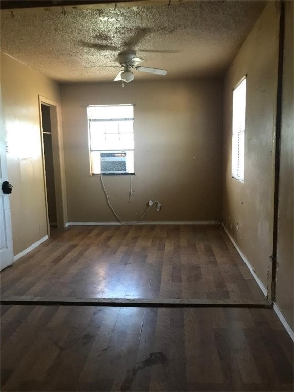 unfurnished room featuring ceiling fan, cooling unit, dark wood-type flooring, and a textured ceiling