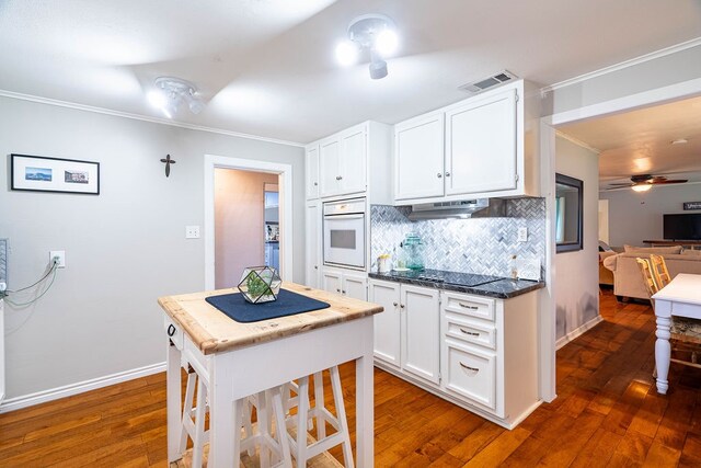 kitchen with white oven, white cabinetry, and dark wood-type flooring