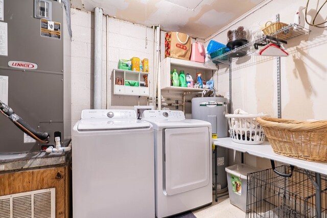 laundry room featuring electric water heater, washer and dryer, and heating unit