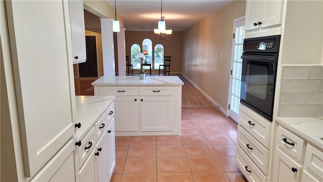 kitchen with white cabinetry, a notable chandelier, pendant lighting, light stone countertops, and oven