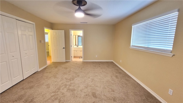 unfurnished bedroom with ensuite bathroom, ceiling fan, a closet, and light colored carpet