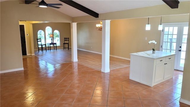 kitchen with a healthy amount of sunlight, vaulted ceiling with beams, decorative light fixtures, and a center island