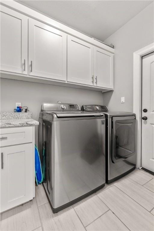 washroom with washing machine and clothes dryer and cabinets