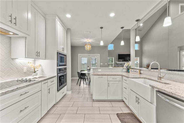 kitchen with light stone countertops, pendant lighting, white cabinetry, stainless steel appliances, and decorative backsplash