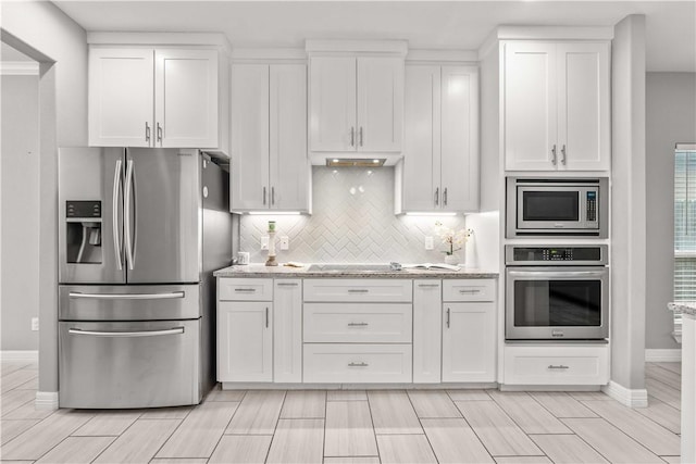 kitchen featuring white cabinets, tasteful backsplash, light stone countertops, and appliances with stainless steel finishes