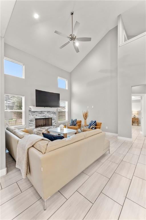 living room with a fireplace, high vaulted ceiling, and ceiling fan