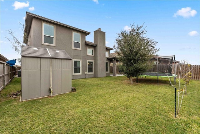 rear view of house featuring a storage unit, a trampoline, and a lawn