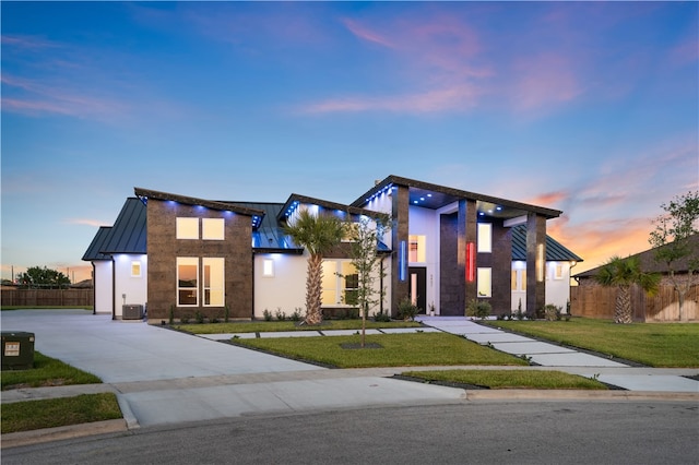 contemporary house with central air condition unit and a yard