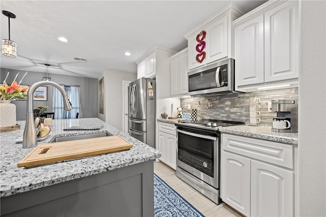 kitchen with sink, white cabinets, hanging light fixtures, stainless steel appliances, and light stone countertops