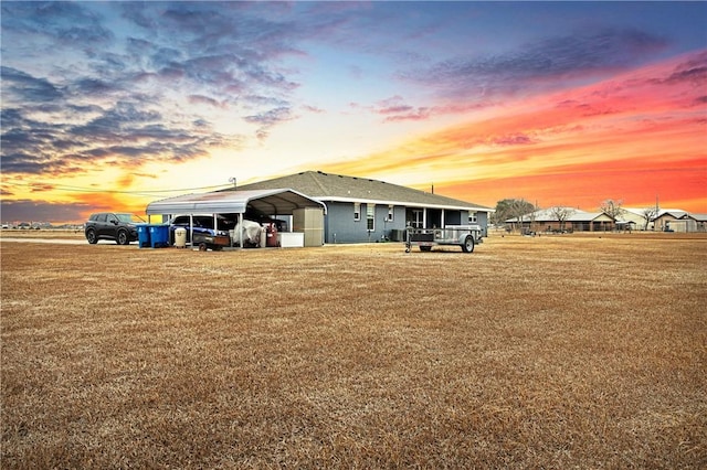 property exterior at dusk featuring a carport and a yard