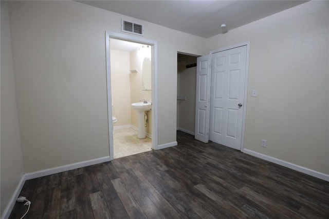 unfurnished bedroom featuring sink, dark hardwood / wood-style floors, a closet, and ensuite bathroom