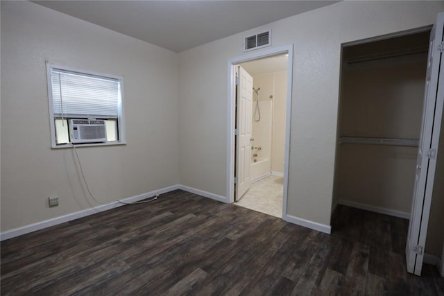 unfurnished bedroom featuring connected bathroom, dark hardwood / wood-style floors, a closet, and cooling unit