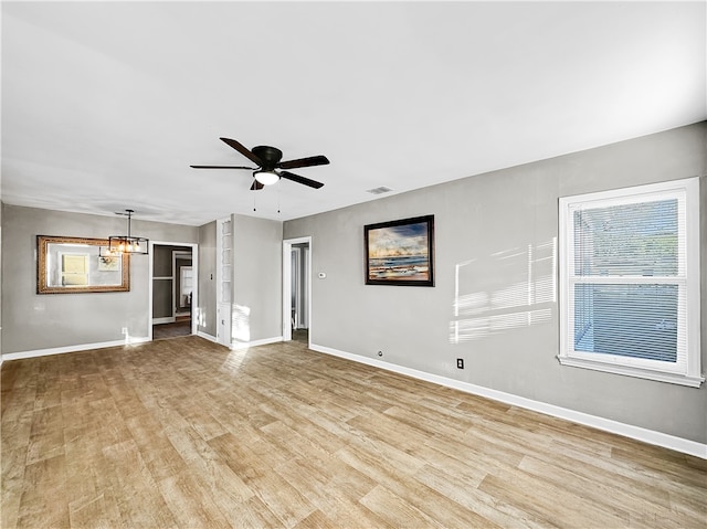 spare room with ceiling fan with notable chandelier and light hardwood / wood-style flooring