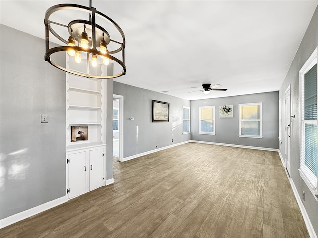 unfurnished living room featuring wood-type flooring and ceiling fan with notable chandelier