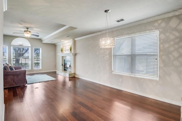 7421 Blue Lake Dr, Corpus Christi, TX 78413 - unfurnished living room featuring dark wood-style floors, a ceiling fan, a tiled fireplace, and ornamental molding