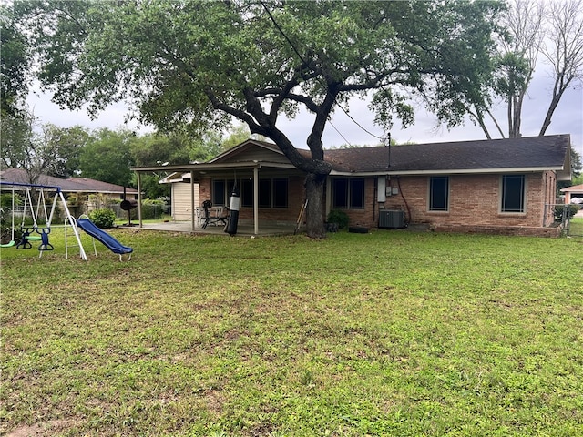 rear view of house with a playground, central air condition unit, a patio, and a yard