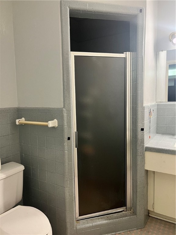 bathroom with toilet, an enclosed shower, and tile walls