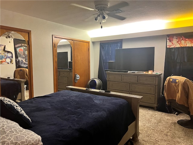 bedroom with ceiling fan, light colored carpet, a textured ceiling, and a closet