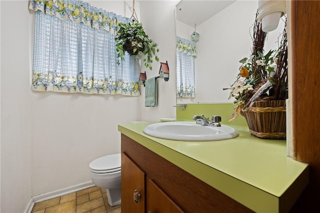 bathroom featuring toilet, vanity, and baseboards