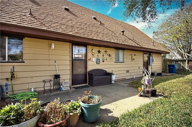 rear view of house featuring a yard, roof with shingles, a patio, and fence