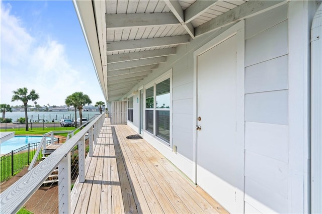 wooden terrace with a water view, a fenced in pool, and fence