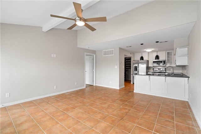unfurnished living room featuring lofted ceiling with beams, visible vents, ceiling fan, light tile patterned floors, and baseboards