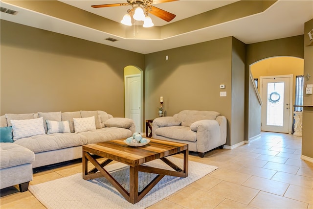 living room with ceiling fan, light tile patterned floors, and a tray ceiling