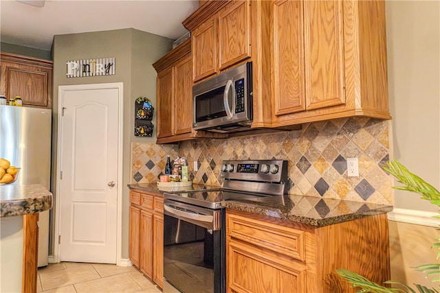 kitchen with dark stone countertops, tasteful backsplash, light tile patterned floors, and stainless steel appliances