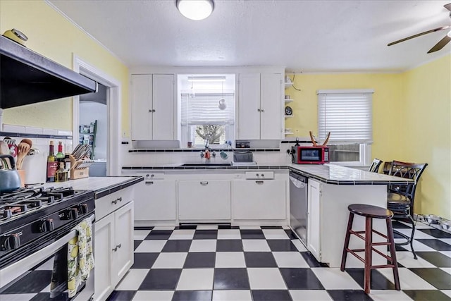 kitchen with stainless steel appliances, range hood, tile countertops, a kitchen bar, and white cabinets