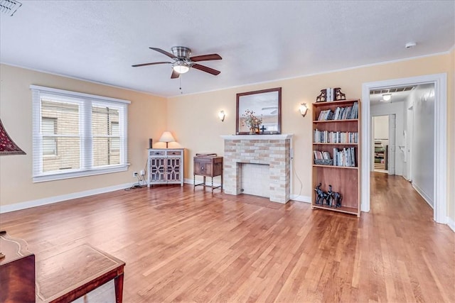 living room with ceiling fan, light wood-type flooring, and a fireplace