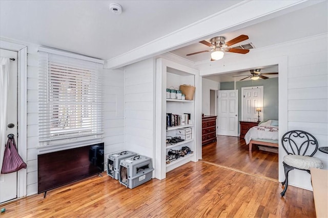 bedroom with beamed ceiling, wood-type flooring, and ceiling fan