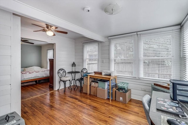 office space featuring beam ceiling, wooden walls, ceiling fan, and wood-type flooring