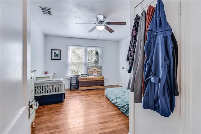 bedroom with ceiling fan, hardwood / wood-style floors, and a textured ceiling