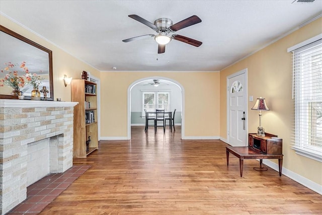 living room featuring a wealth of natural light, ceiling fan, hardwood / wood-style flooring, and a brick fireplace