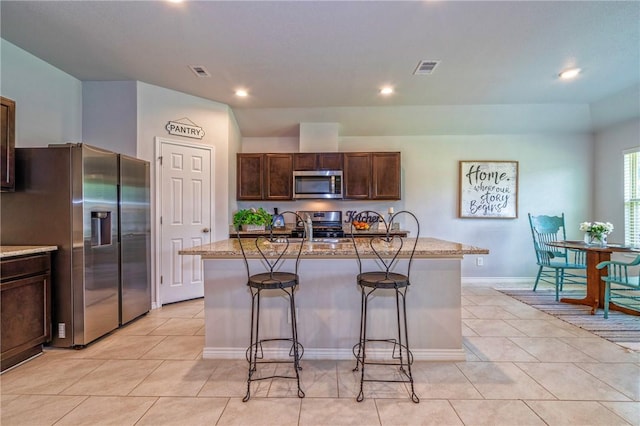 3922 Jayden Dr, Corpus Christi, TX 78410 - kitchen with appliances with stainless steel finishes, recessed lighting, a breakfast bar area, light tile patterned floors, and an island with sink