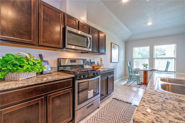 3922 Jayden Dr, Corpus Christi, TX 78410 - kitchen with stainless steel appliances, dark brown cabinetry, vaulted ceiling, light tile patterned flooring, and light countertops