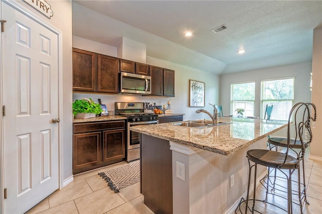 3922 Jayden Dr, Corpus Christi, TX 78410 - kitchen with stainless steel appliances, light tile patterned flooring, a kitchen breakfast bar, an island with sink, and light stone counters