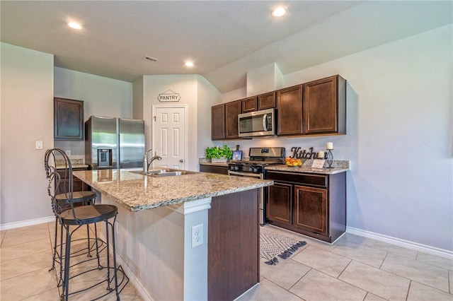 3922 Jayden Dr, Corpus Christi, TX 78410 - kitchen with appliances with stainless steel finishes, a kitchen bar, dark brown cabinets, a center island with sink, and light stone counters