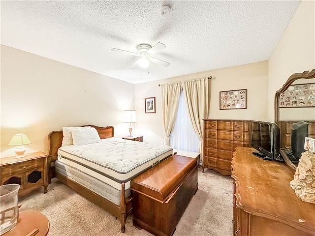 bedroom featuring ceiling fan, a textured ceiling, and light carpet