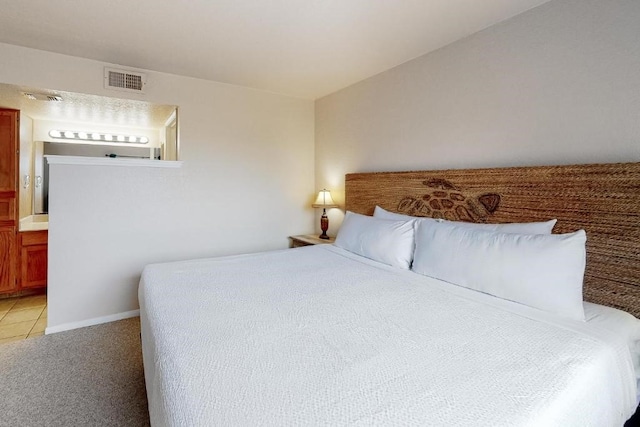 bedroom featuring connected bathroom and light carpet