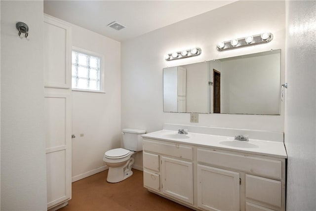 bathroom with toilet, double vanity, visible vents, and a sink